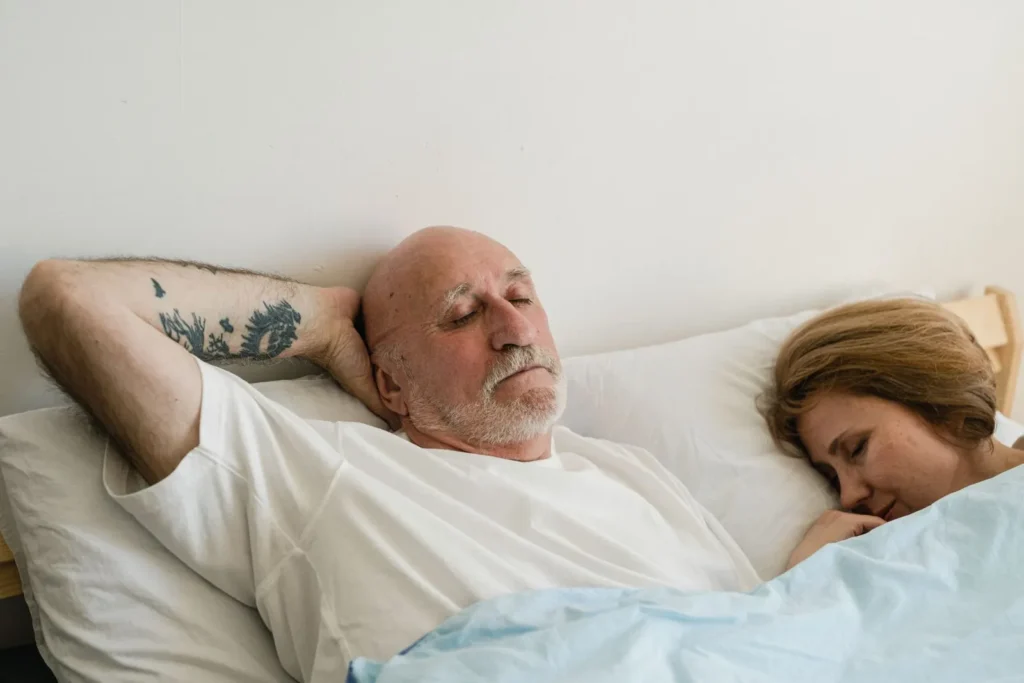 Older couple sleeping side by side in bed