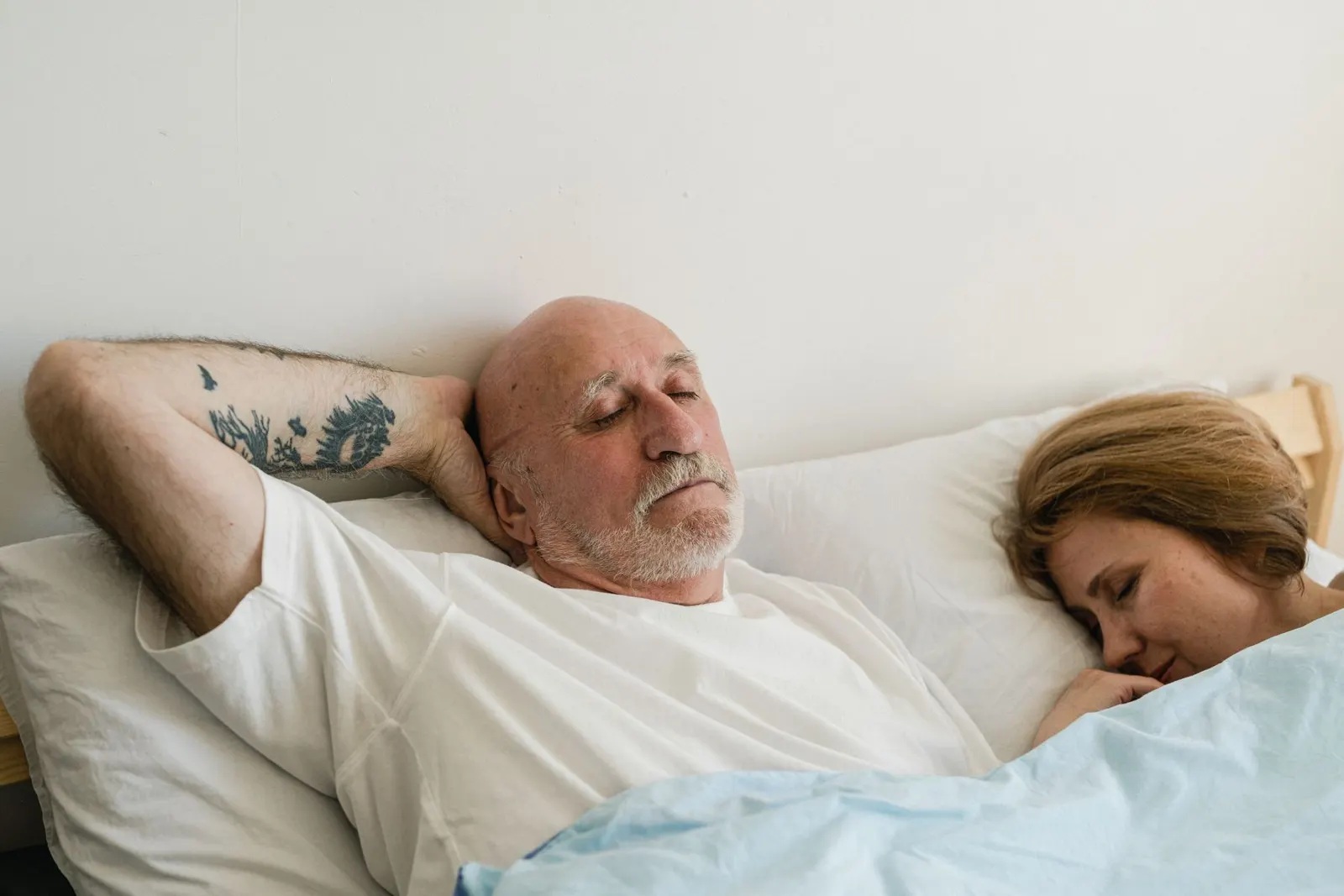 Older couple sleeping side by side in bed