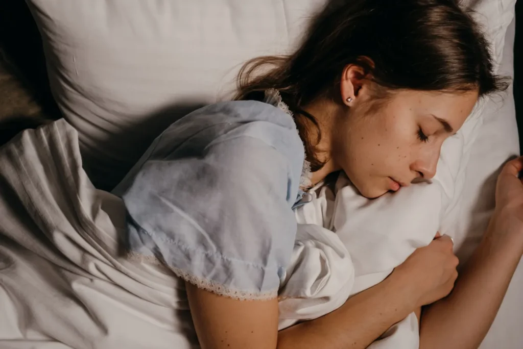 Young woman sleeping on a white pillow at night