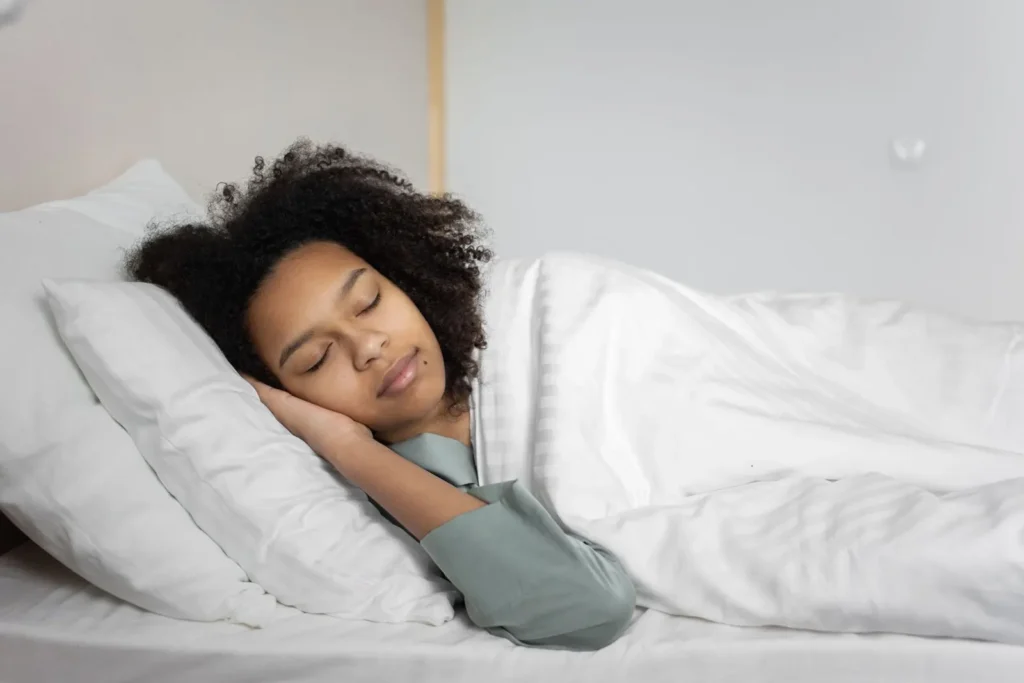 Woman with afro hair sleeping in a cozy bedroom