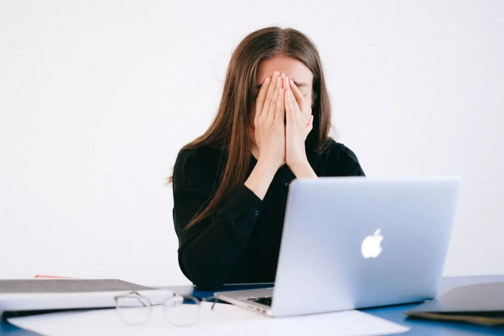 Woman feeling stressed at her desk while working on a laptop