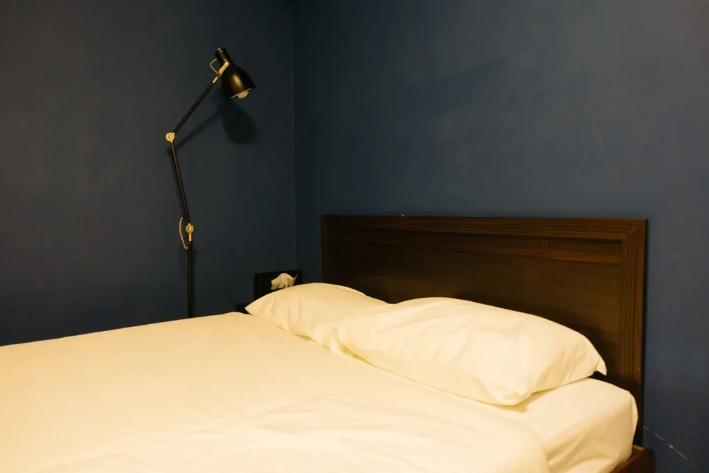 Minimal bedroom with a dark blue wall and a lamp